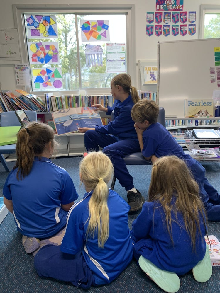 Older student reading to younger students